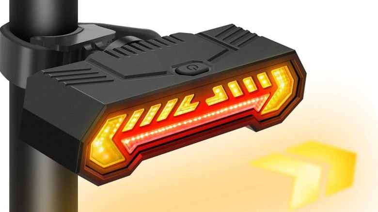 A black Vcwtty plastic taillight mounted to a pole, illuminating arrows in orange.