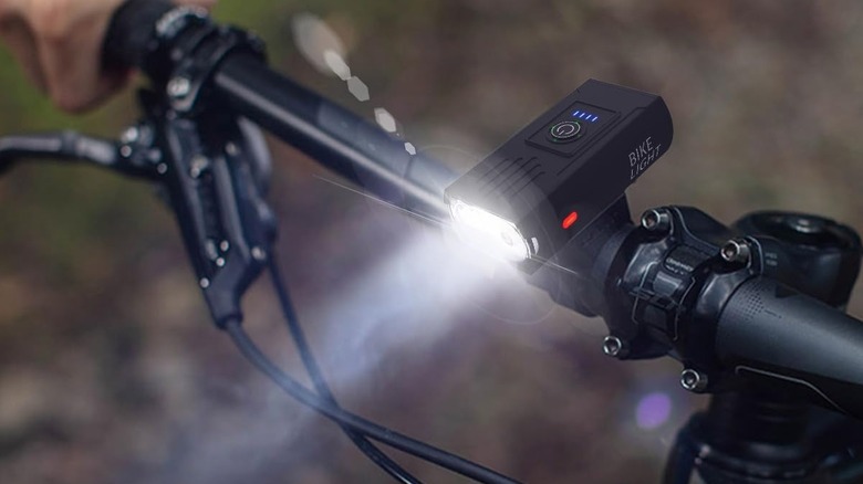 A black, rectangular bike light mounted to a handlebar, shining through a foggy night.