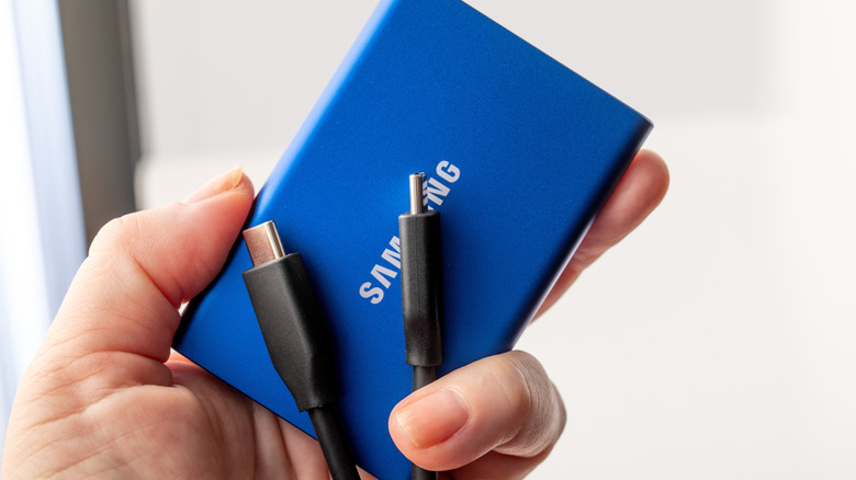 A person holding a Samsung SSD with a cable