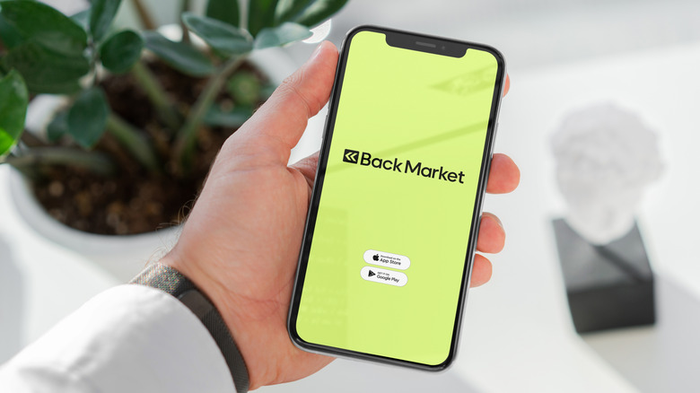 A person holding a phone with the Back Market logo on the screen.