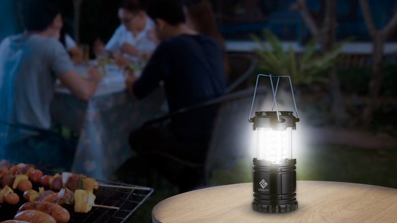 An Etekcity lantern on a table, being used to light up a nighttime barbecue.