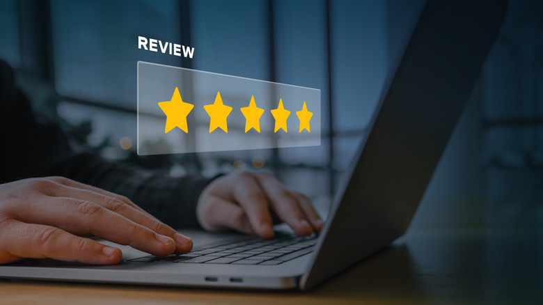 A holographic image of five-star review above hands on a laptop keyboard