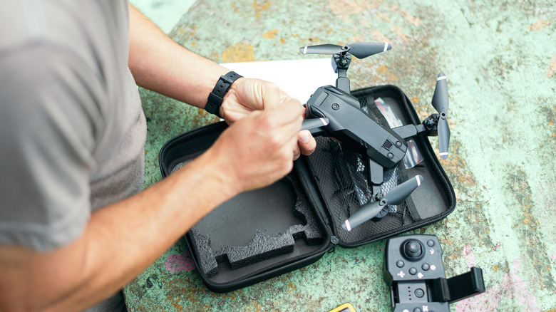 A close-up view of someone setting up or maintaining a compact foldable consumer drone.