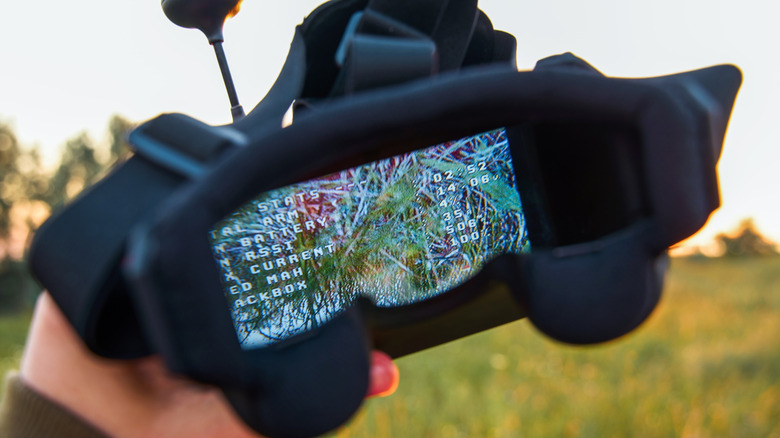 A close-up photo of FPV (first-person view) drone goggles being held outdoors.