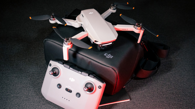 A product-style photo showing a compact foldable consumer camera drone, a matching remote controller, and a carrying case.