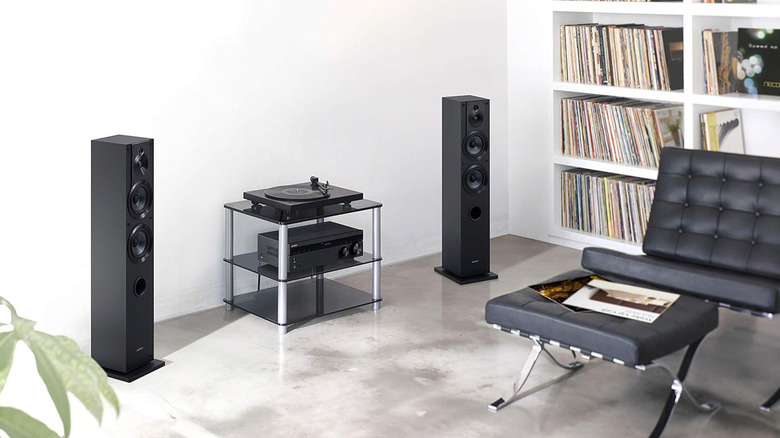 A living room with Sony speakers, a stereo receiver, a turntable, and a modern leather couch.