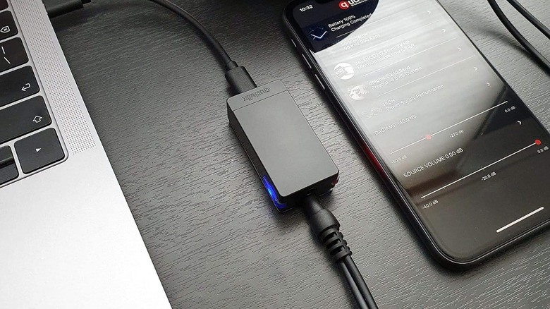 A Qudelix 5K on a table with a MacBook and smartphone.
