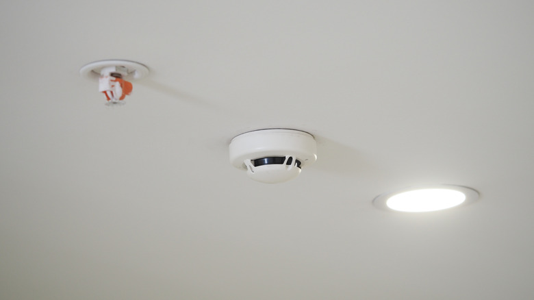 Ceiling-mounted smoke detector installed alongside a fire sprinkler.