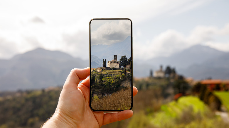 A person taking a photo of a landscape using their smartphone.