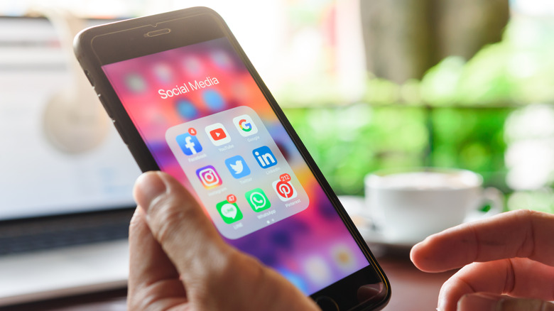 Hands of an old man use Iphone 7 plus with social media of facebook