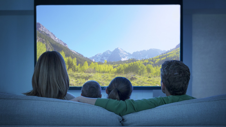 A family watches a movie at home using a projector.