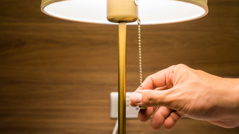 Person pulling on a nightlamp chain to turn it off