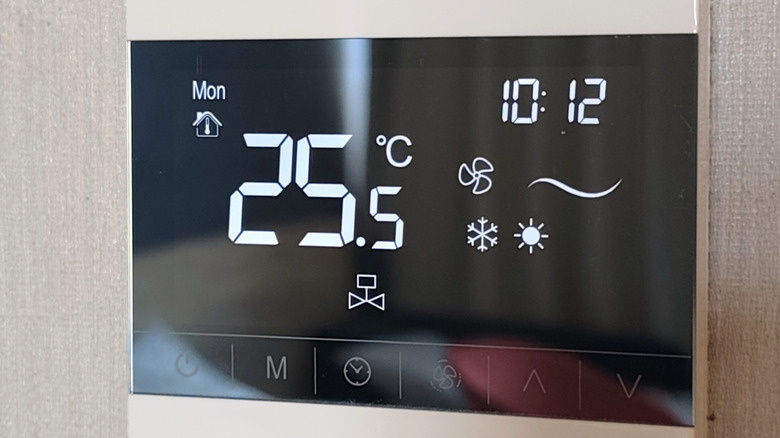 A digital thermostat on the wall of a home