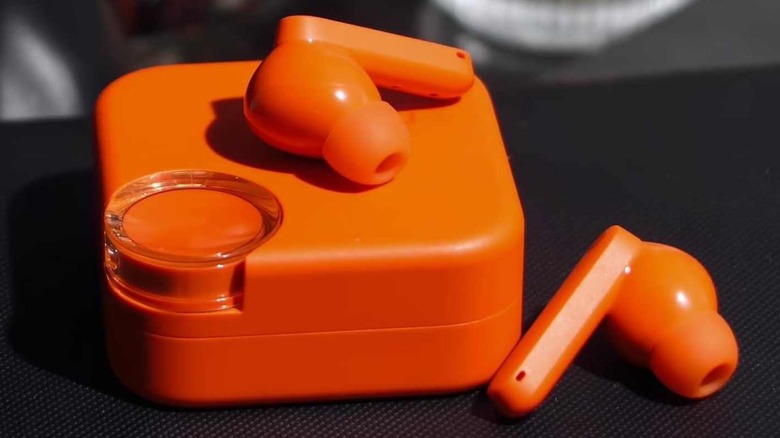 The orange CMF Buds 2 on a black countertop.