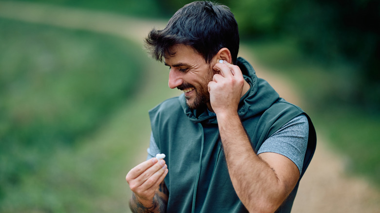 A man adjusting his earbuds in the park