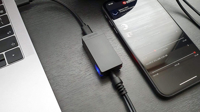 A Qudelix 5K on a desk with a smartphone and laptop