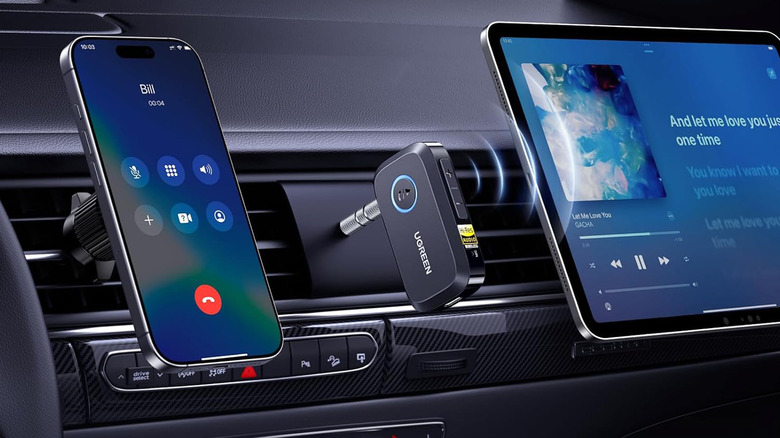 A Ugreen car adapter next to a smartphone and infotainment screen on a car dashboard.