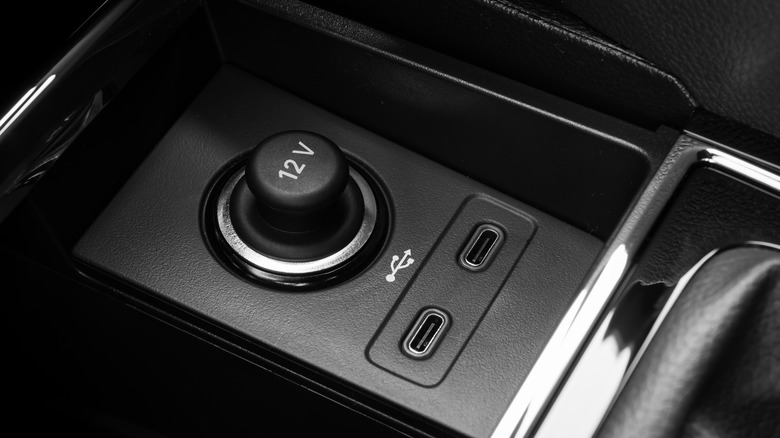 Two USB ports next to a 12-volt outlet in a car.