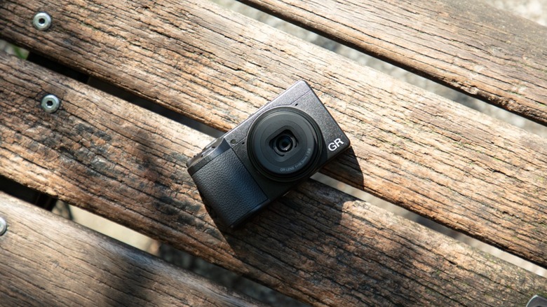 A Ricoh GR IV camera against a background of wooden slats
