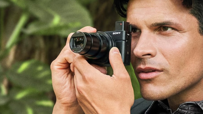 A person holding a Sony RX100 VII and using the electronic viewfinder to shoot photos