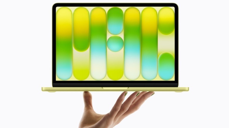 A product render showing a person holding up the MacBook Neo laptop.