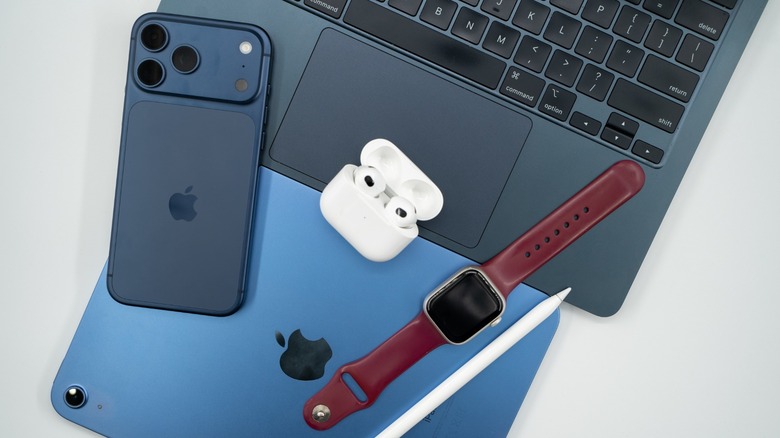 A MacBook, iPad, and iPhone alongside various Apple accessories