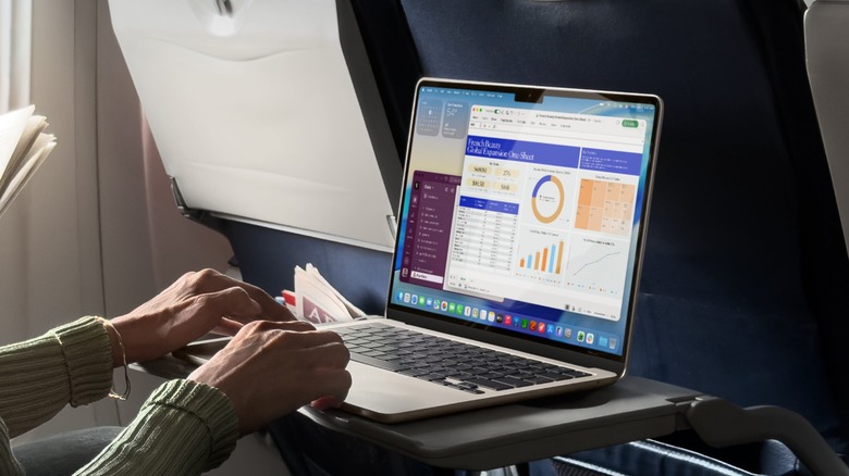 A person using an M5 MacBook Air on a plane
