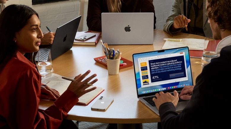People using MacBooks in a business meeting