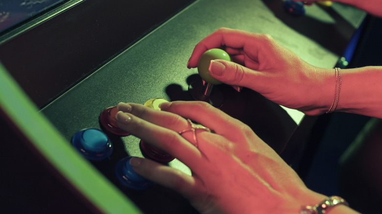 Hands operating a classic arcade cabinet.