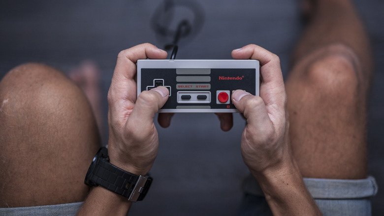 Close-up of hands holding a classic Nintendo-style game controller.