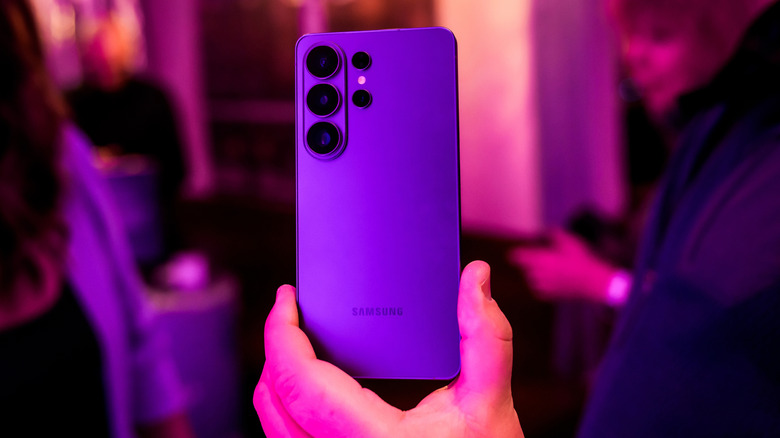 Samsung Galaxy S26 held up by someone with purple hue in the room.