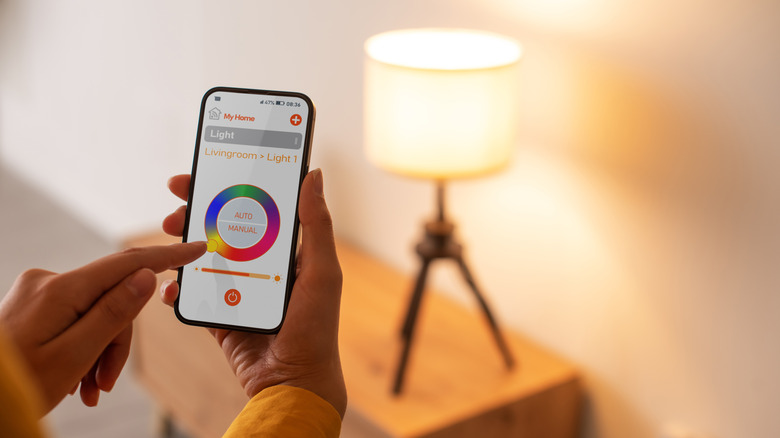 A person adjusting a smart bulb's settings through an app on their phone
