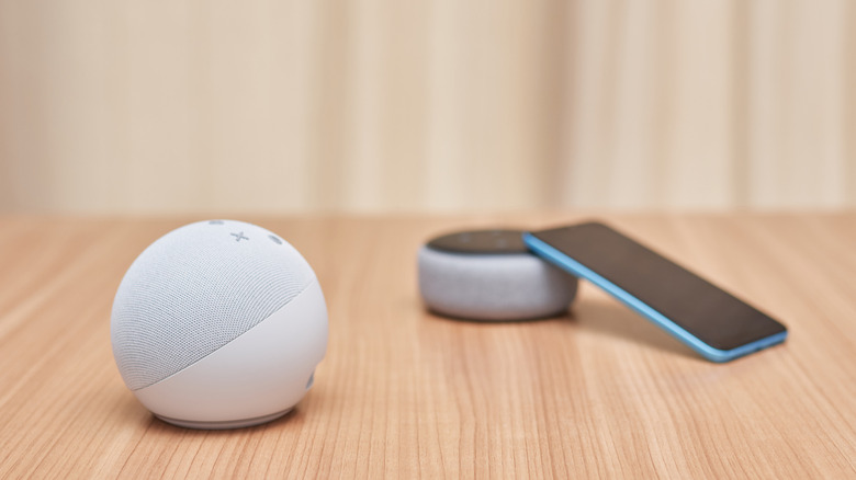 Amazon Echo smart speakers on a desk with a smartphone
