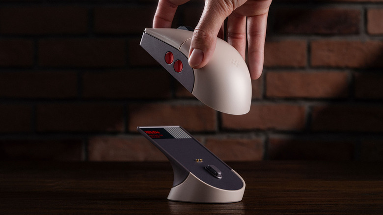 A hand placing the NES-inspired 8BitDo Retro R8 on its charging dock by