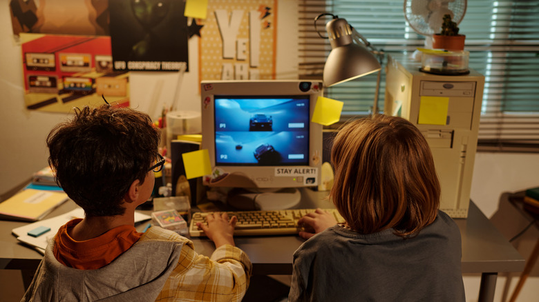 Two kids playing a racing game on a CRT