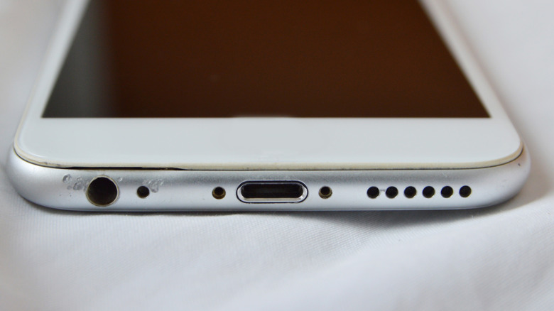 A damaged-looking headphone port on an iPhone.