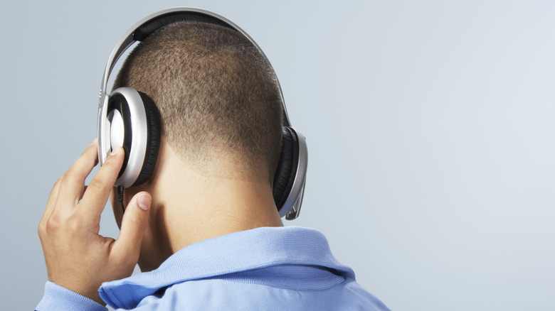 A man, facing away, listening to headphones.