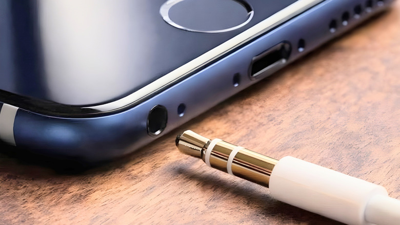 A headphone cable going into an audio jack on an iPhone.