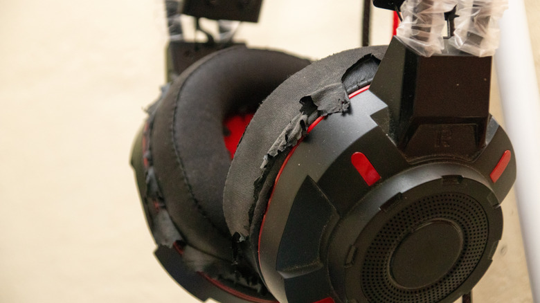 A pair of headphones that have scuffed-up ear pads.
