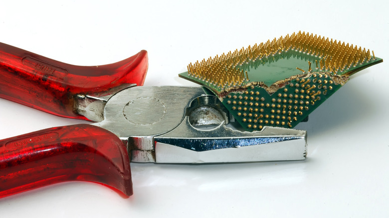Pair of pliers crushing a computer processor.