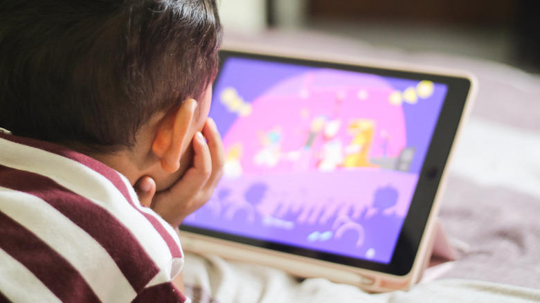 A boy watching a video for kids on a tablet.
