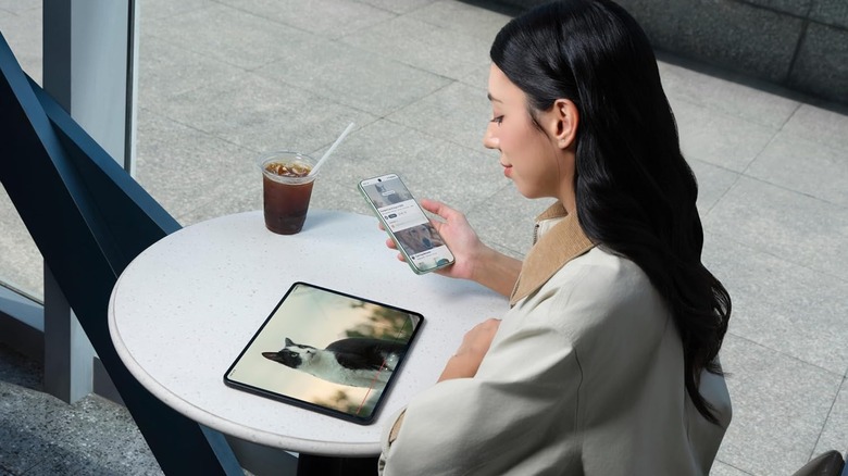 A woman watching a video of a cat on the OnePlus Pad Go 2 tablet while holding a smartphone.