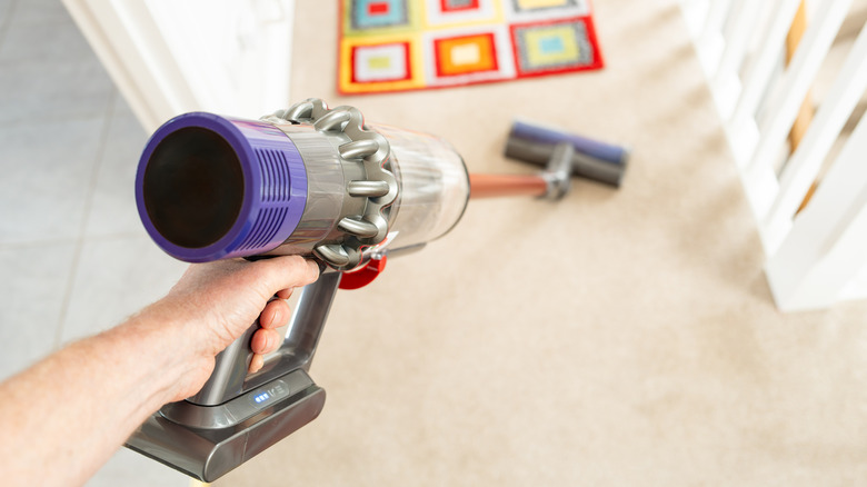 A person using a cordless vacuum to clean the floor.