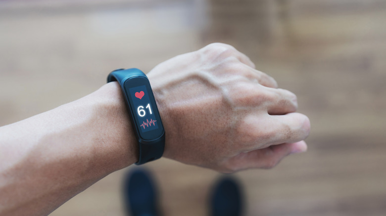 A person wearing a fitness tracker showing their heart rate.