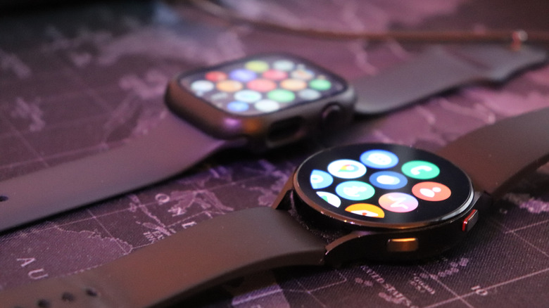A square-faced Apple Watch and a round-faced Samsung watch lie side by side on a table.