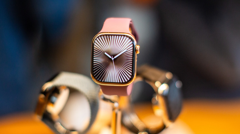 Three Apple watches arranged in a display with a blurred background.
