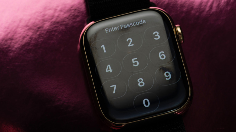 The passcode screen on an Apple Watch in front of a maroon fabric background.