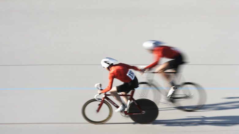 Two cyclists in a relay race, with one blurred and the other cleared.