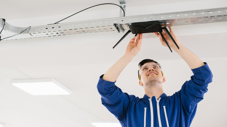 Man in blue jacket installing a router on ceiling