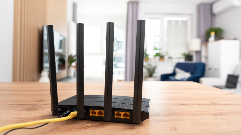 Black router with four antennas placed on a wooden table